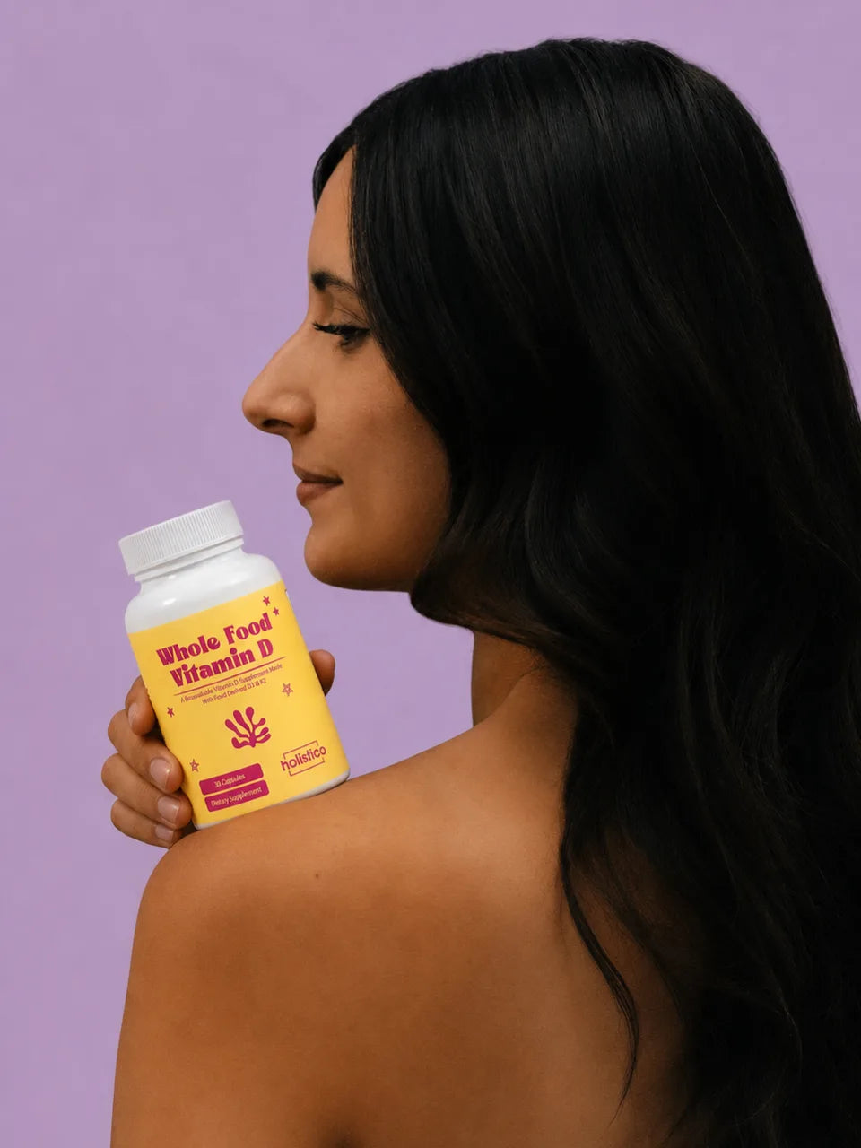 A woman in profile holding a bottle of Whole Food Vitamin D on her shoulder against a lilac background