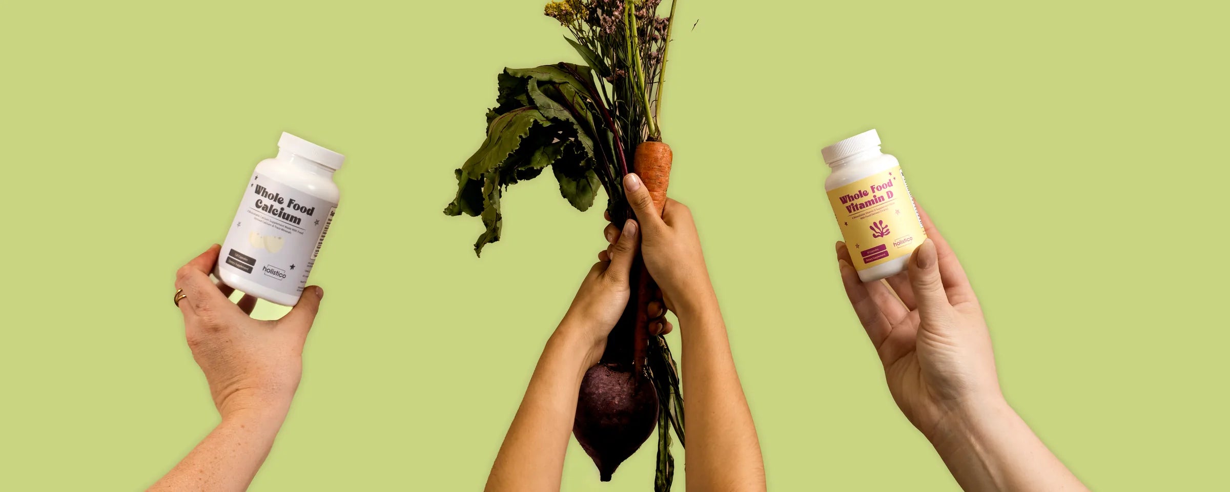 Three raised hands against a green background — one holding Holistico Whole Food Calcium, one holding Whole Food Vitamin D, and one holding a bunch of carrots, beetroot and wildflowers between them